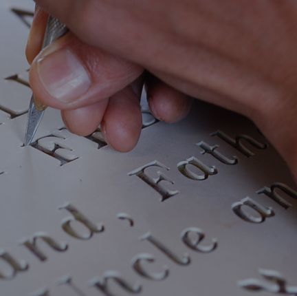 A hand cutting letters into granite