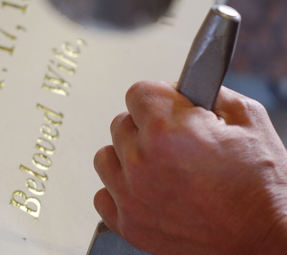 A chisel cutting gilded lettering